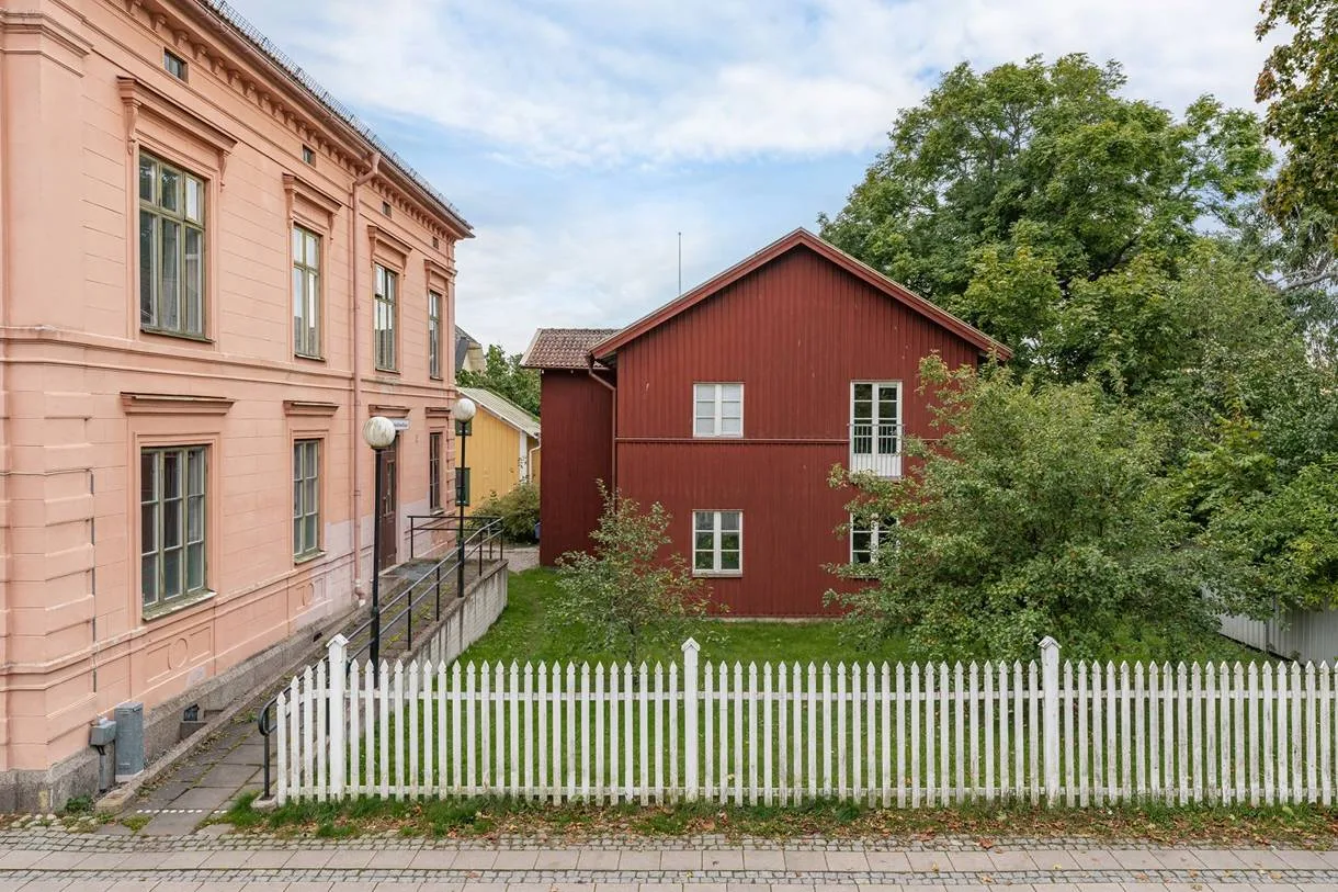 Stenhuset och det röda trähuset bakom det vita staketet