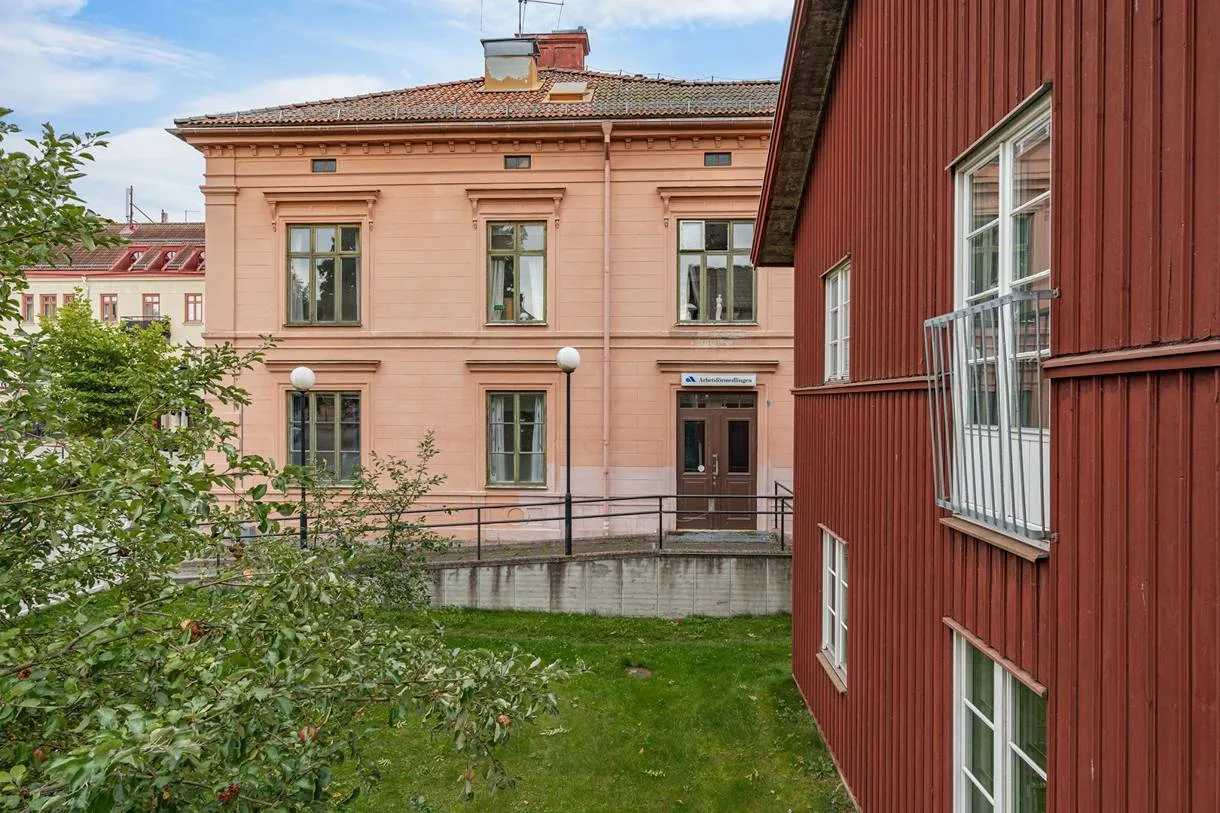 Stenhusets gavel sedd från trädgården, med det röda trähuset till höger