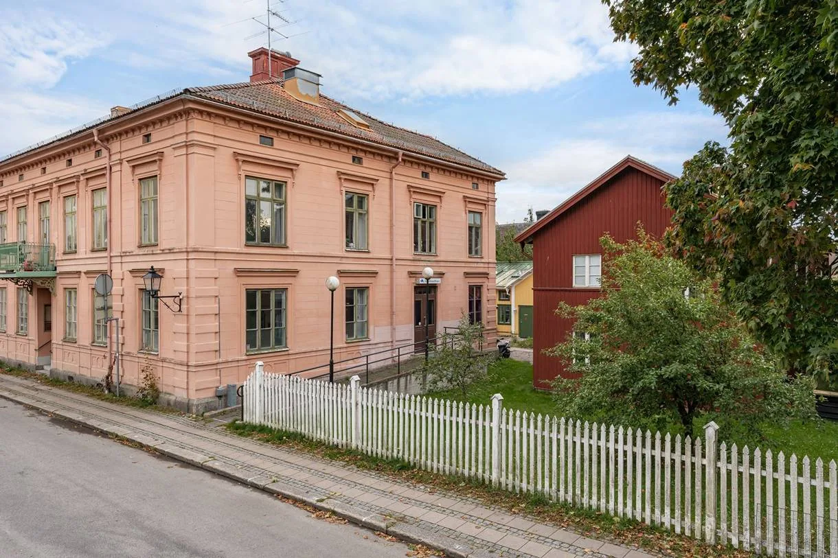 Fastigheten från gatan: stenhus, trähus och vitt staket